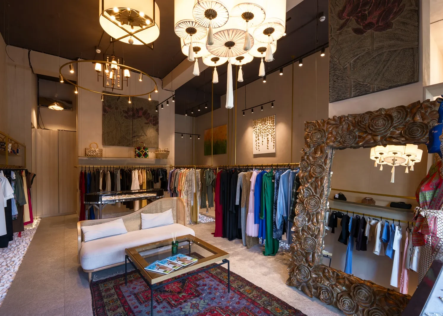 Зал Zehni Store в Sea Breeze: вешала с платьями и жакетами, зеркало в резной раме с розами, белый диван на красном ковре, картины на стенах